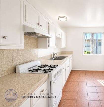 A kitchen with a white stove and white cabinets.