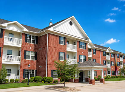A red brick apartment building with a white front entrance and a small porch.