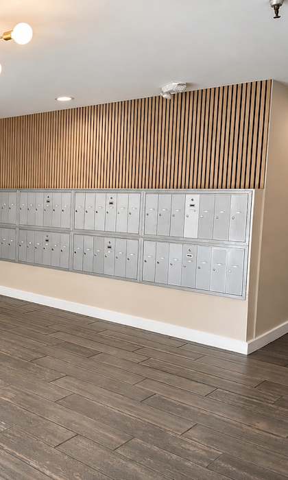 A room with a wooden floor and a wall with a row of lockers.