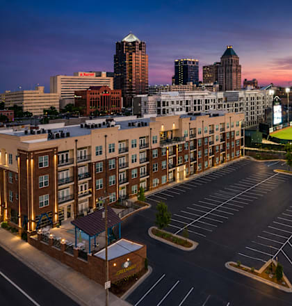 A parking lot is shown in front of a building with a baseball field in the background.