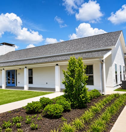 A white house with a blue door and a grey roof.