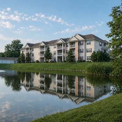 A large building is reflected in a lake in front of it.