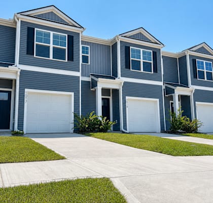 A row of houses with garages and front yards.