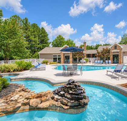 A large outdoor swimming pool with a rock feature in the middle.