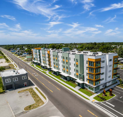 A modern apartment building with a parking lot in front.