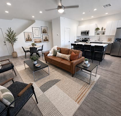 A modern living room with a brown leather couch and a glass coffee table.
