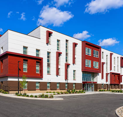 A modern building with a red and white facade and a yellow mural on the side.