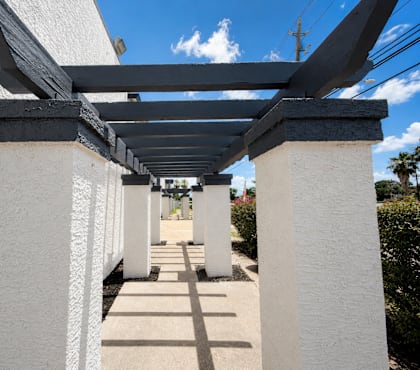 A long corridor with white walls and a roof supported by white pillars.