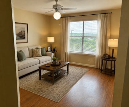 A living room with a couch, a table, and a ceiling fan.
