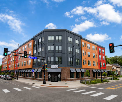 A street view of a multi-story building with a black facade and a red facade on the side.
