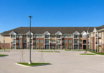 A blue and white townhouse with a front yard and a driveway.at Hawthorne Pointe, Bondurant, IA