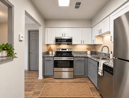 A modern kitchen with stainless steel appliances and a grey door.