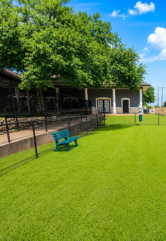 A backyard with a green lawn and two blue benches.
