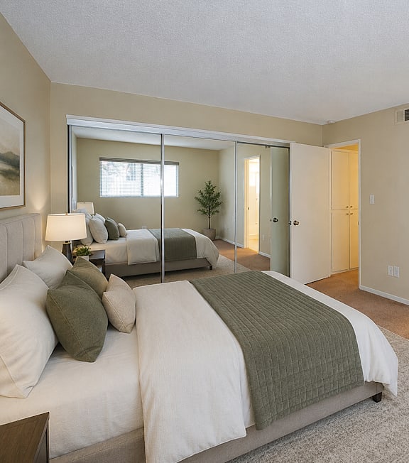 A well-lit bedroom with a large bed and a painting on the wall.