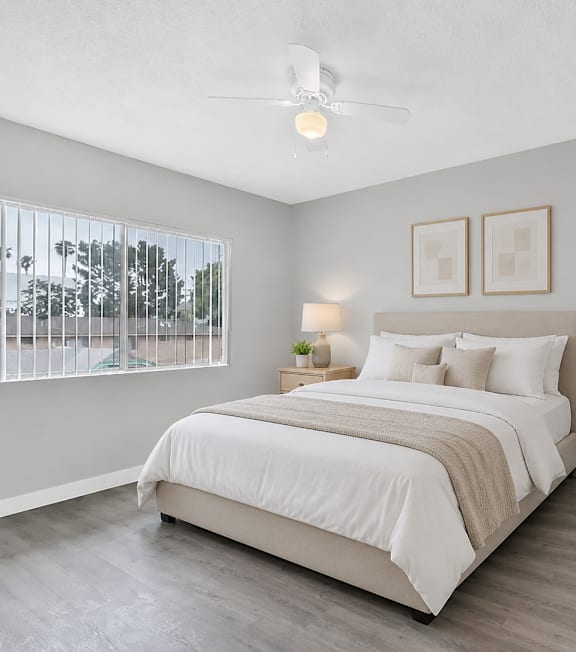 A well-lit bedroom with a large bed and a painting on the wall.