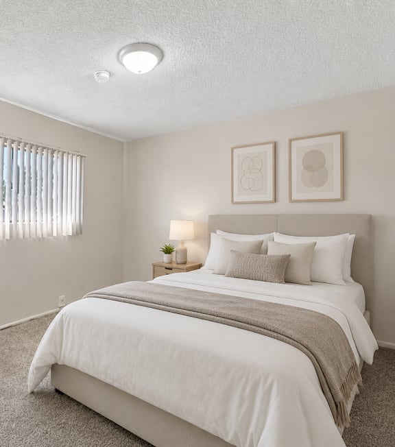 A well-lit bedroom with a large bed and a painting on the wall.
