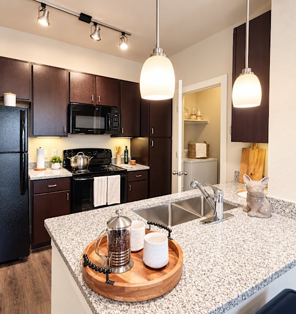 A kitchen with black appliances and brown cabinets.