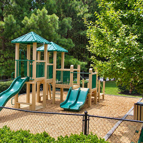 A playground with a green slide and a wooden structure.