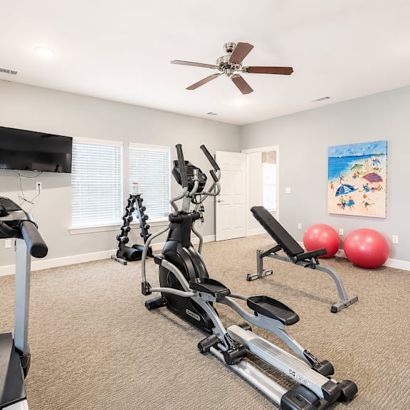 A home gym with a treadmill, exercise bike, and weights.