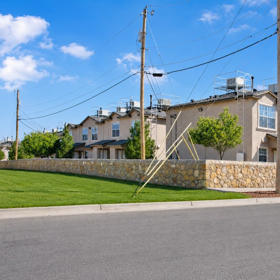 A row of houses with a stone wall in front.