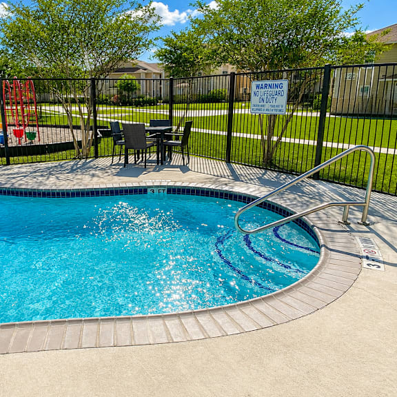 A pool with a warning sign on the fence.