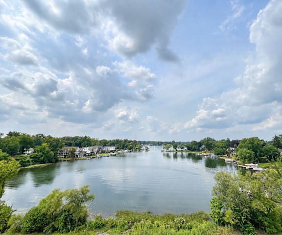 A serene lake surrounded by lush greenery under a partly cloudy sky.