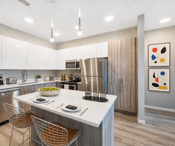 A modern kitchen with a white countertop and stainless steel appliances.