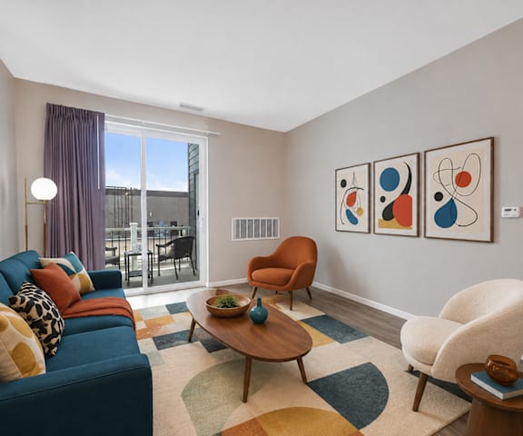 A living room with a blue couch, a wooden coffee table, and a large window with a view of the city.