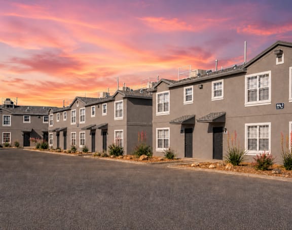 A row of houses with a pink and purple sky in the background.