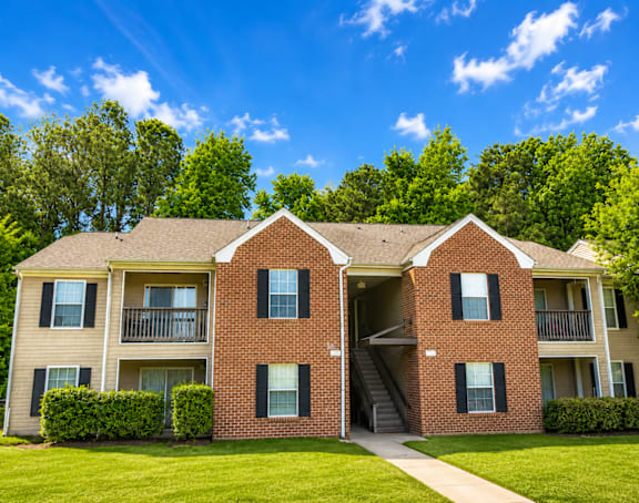 A two-story brick apartment building with a green lawn in front.