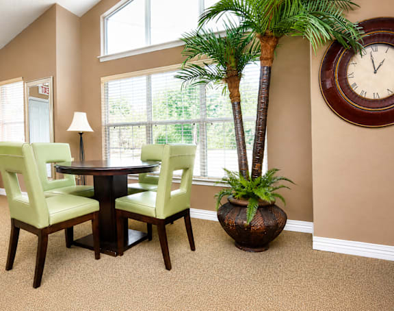 A dining room with a table, chairs and a clock on the wall.