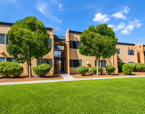 A building with a green lawn in front and trees around it.