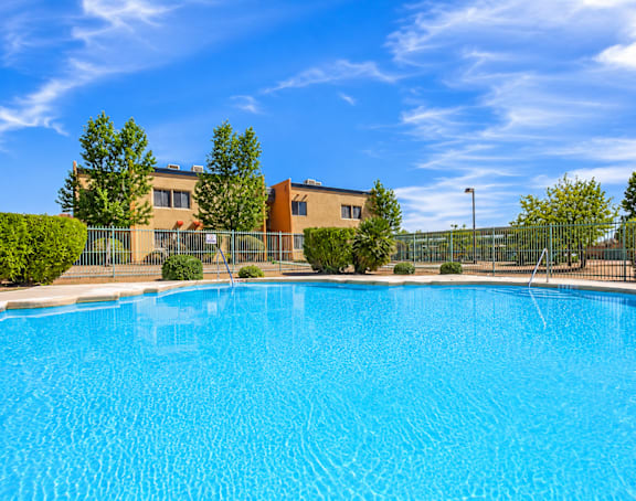 A swimming pool in front of a building with a fence around it.