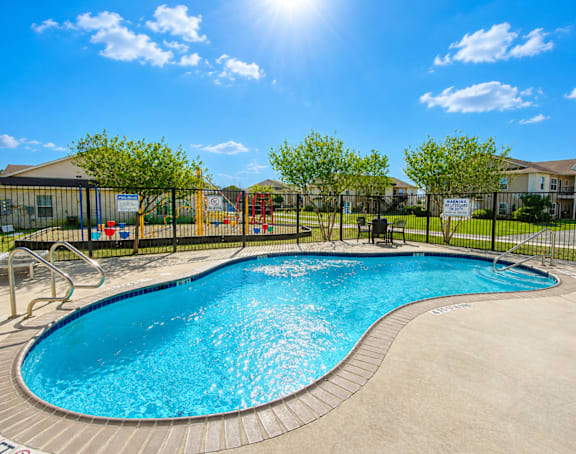 A sunny day at a pool with a slide and a playground.
