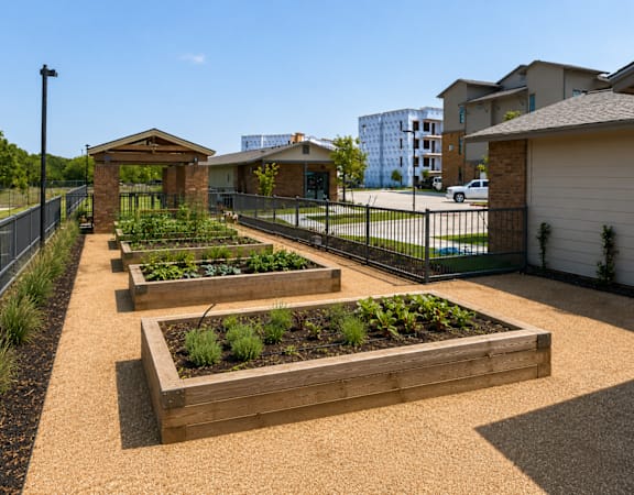 Community garden with raised planting beds and walking paths at One Preston Station Apartments.