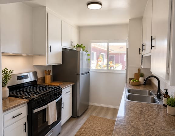 A kitchen with a stove, refrigerator, and sink.