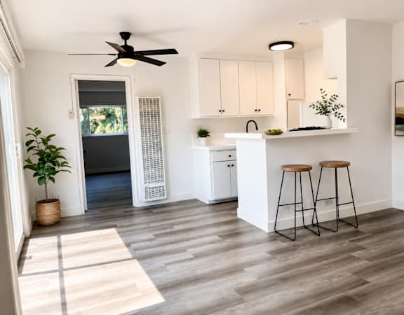A kitchen with white cabinets and a white island with two stools.
