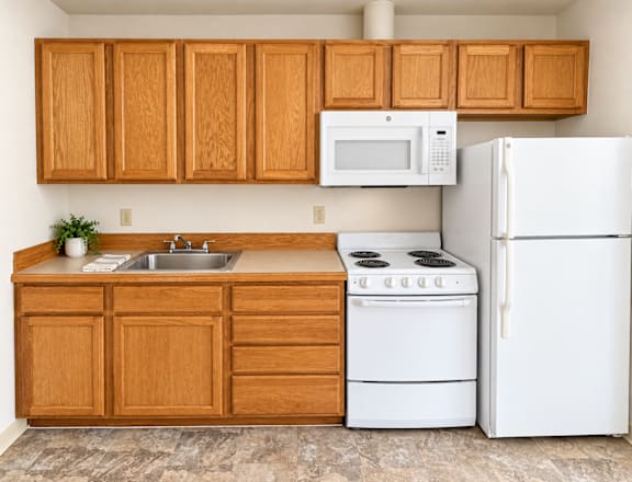 A kitchen with white appliances and wooden cabinets.
