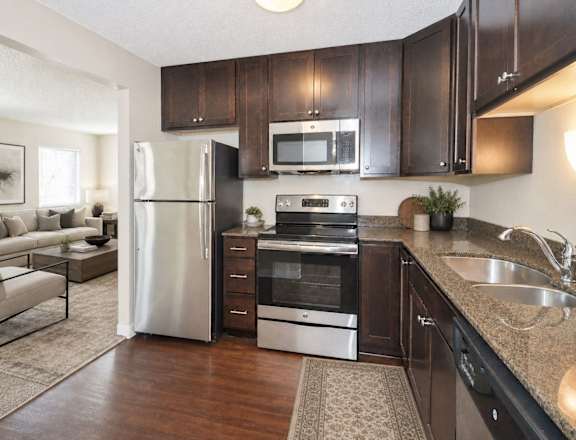 A kitchen with dark brown cabinets and a stainless steel refrigerator.