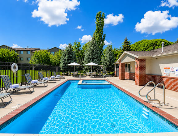 A swimming pool surrounded by lounge chairs and umbrellas.