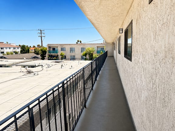 A long concrete walkway with a black railing on the left side and a building on the right side.