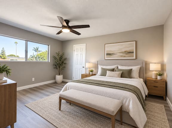 A bedroom with a large bed, a bench, and a ceiling fan.