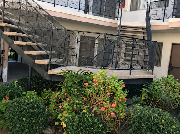 A staircase with a black railing and a building in the background.