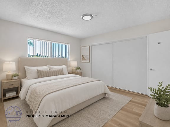 A bedroom with a large bed, a nightstand with lamps, a window with blinds, a rug, a potted plant, and a sliding door.