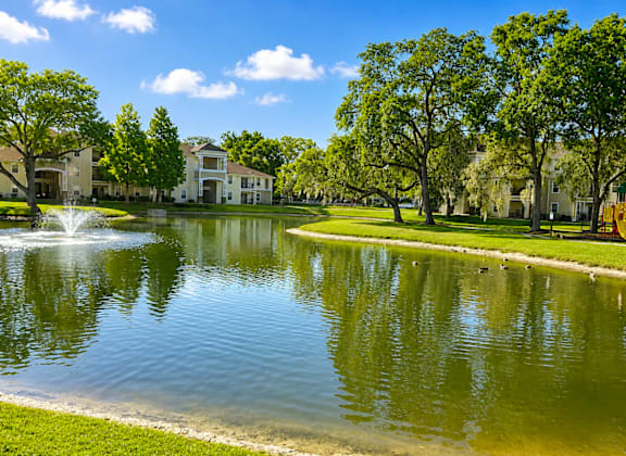 A serene lake in a park with a building in the background.