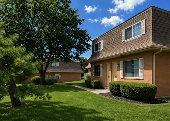 A house with a brown roof and a green lawn.