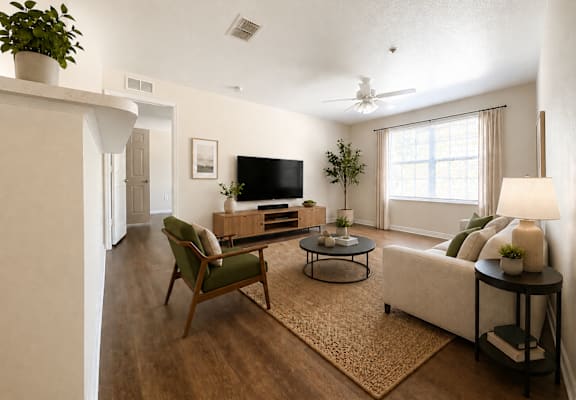 A living room with a green chair, a black television, and a white sofa.