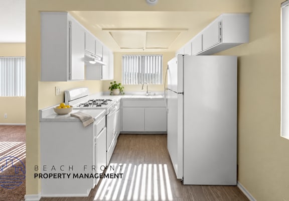 A kitchen with a refrigerator, sink, and stove.