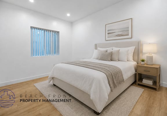 A bedroom with a large bed, a nightstand, and a window with blue curtains.
