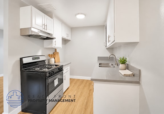 A modern kitchen with a black stove top oven and white cabinets.